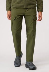 Olivgröna cargobyxor med cargofickor, raka ben och en slät yta, tillsammans med grå vandringsskor.