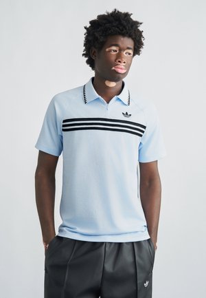 Polo azul claro con cuello, rayas horizontales negras y blancas, y logo de adidas. Mangas raglán con tejido texturizado.