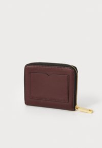 Portafoglio in pelle bordeaux con una cerniera nera, dotato di uno slot per schede frontale, hardware dorato e una texture liscia.