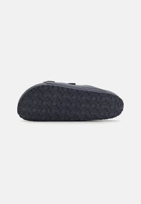 Chaussure slip-on navy avec une semelle en caoutchouc texturée arborant un motif en nid d'abeille, un bout arrondi et un design minimaliste. Idéale pour un usage décontracté.