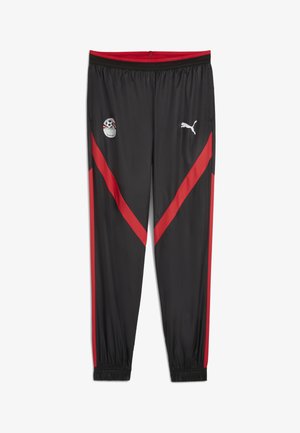 Pantaloni da tracksuit neri con strisce diagonali rosse, vita elastica e polsini. Presenta toppe con logo sulla coscia sinistra e parte superiore della gamba. Realizzati in materiale liscio.