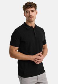 Black knitted polo shirt with a collar, short sleeves, and a textured fabric. Features a three-button placket and ribbed hem.