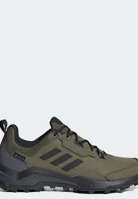 Olivově zelená turistická obuv s texturovaným svrškem, černými akcenty, gumovou podrážkou a třemi černými pruhy. Obsahuje branding GORE-TEX a tkaničky.