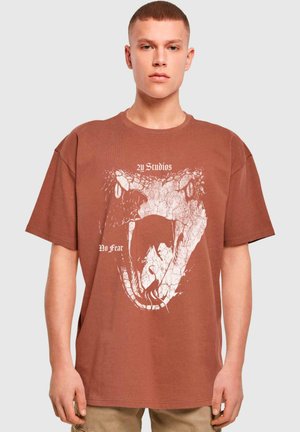 Brown oversized cotton t-shirt featuring a white snake graphic and text "2Y Studios No Fear" in a bold font on the front.