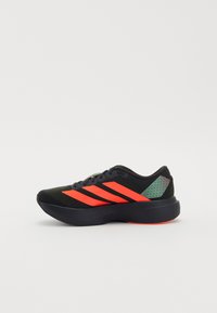 Black athletic shoe with neon orange accents, featuring a textured knit upper and a molded heel. Designed for comfort and performance.