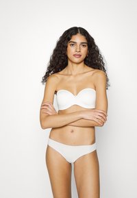 Witte strapless bh met een gladde textuur en subtiele cupvorm, gecombineerd met witte low-rise onderbroek. Eenvoudig ontwerp, geen zichtbare hardware.