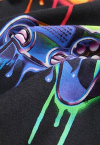 Čierny textil s pestrofarebným grafickým tlačom herného ovládača so modrými, zelenými a fialovými akcentmi, a štruktúrovaným vzorom.