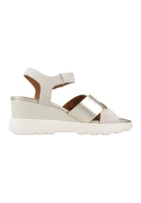Sandalias cuña con un upper de ante beige y una tira cruzada metálica dorada, correa de tobillo ajustable y una gruesa suela de goma blanca.