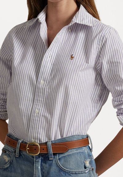 Svetlo purpurna in bela črtasta srajca s ovratnikom, slim fit, z majhnim vezenim logotipom. Nosen z rjavim pasom in jeans kratkimi hlačami.