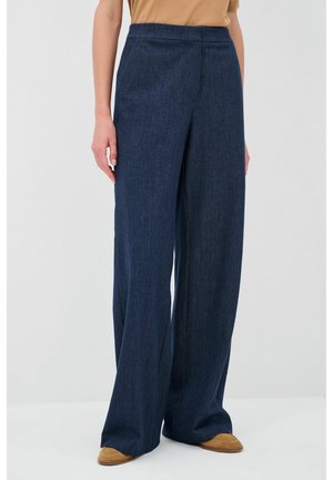 Pantalons à jambes larges en denim foncé. Dotés d'une taille haute et de lignes épurées, associés à des chaussures à enfiler marron.