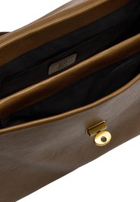 Brązowa skórzana torebka o gładkiej powierzchni, wyposażona w złote zapięcie na zatrzask oraz dwa przegródki wyłożone ciemnym materiałem.