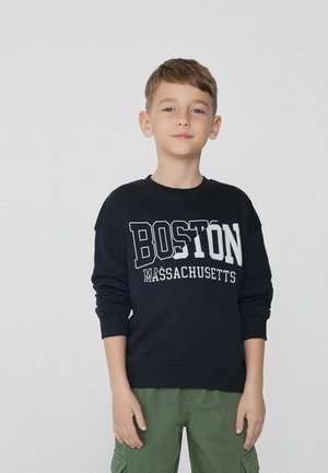 Marinefarbener Sweatshirt mit großem "BOSTON" und "MASSACHUSETTS" in weißem Text. Rundhalsausschnitt, lange Ärmel und gerippte Bündchen. Getragen mit grünen Cargo-Hosen.
