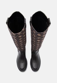 Botas negras hasta la rodilla con parte superior de tejido marrón con patrón, sección inferior negra suave y detalles decorativos de metal.