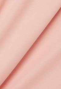 Tissu rose clair à la texture lisse, présentant un motif côtelé diagonal subtil et des plis créant des ombres douces.