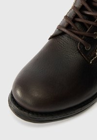 Braune Leder-Ankle-Boots mit runder Zehenpartie, strukturiertem Obermaterial und kontrastierender Naht. Verfügt über braune Schnürsenkel und metallische Ösen.