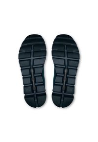 Les semelles de chaussures de sport noires présentent un motif texturé avec des rainures et des grips prononcés, conçus pour l'adhérence et la stabilité pendant le mouvement.