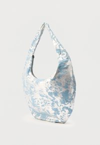 Blød skuldertaske i stof med blå og hvidt abstrakt blomsterprint og lynlås i toppen, vist mod en ensfarvet lys baggrund.