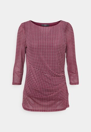 Camiseta de manga larga color morado con un pequeño estampado geométrico blanco y cuello redondo sobre un fondo liso.