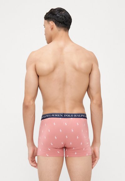 Roza bokserice s ponavljajočim se vzorcem belega polo logotipa, z mornarsko modrim pasom z besedilom "POLO RALPH LAUREN". Mehek, raztegljiv material.