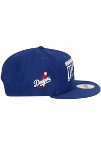 Blaue Kappe mit flachem Schild, auf dem der weiße Schriftzug "Dodgers" und eine rote Baseballgrafik zu sehen sind. Hergestellt aus Stoff mit einer strukturierten Oberfläche.