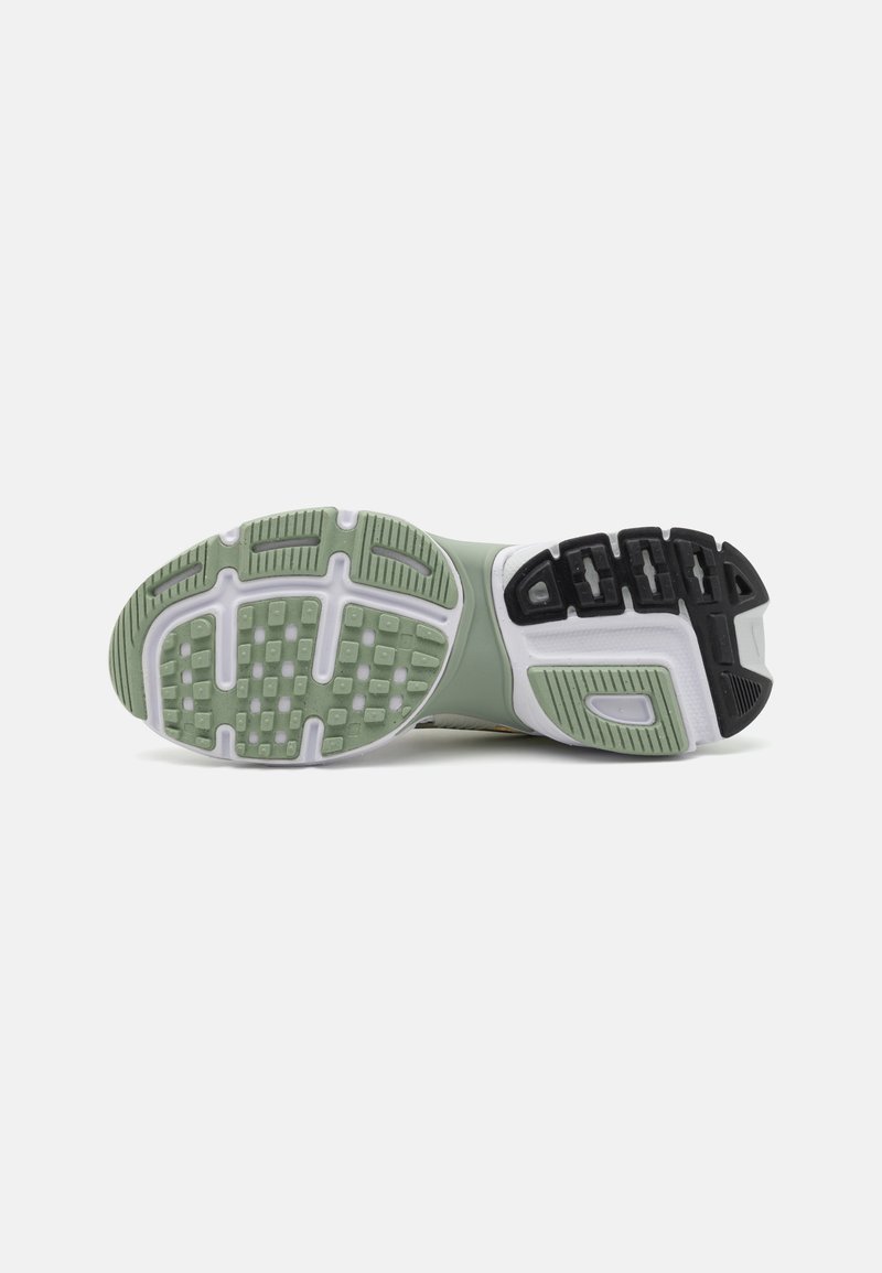 Semelle de chaussure de sport verte et noire avec du caoutchouc texturé, présentant un motif de bande de roulement pour une meilleure adhérence, et une transition douce vers un intersemelle en caoutchouc blanc.