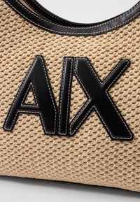 Knit tan bag with a textured surface, featuring a prominent black leather logo "AIX" and contrasting beige stitching along the edges.