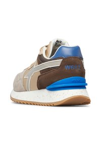 Scarpa sportiva bicolore con suede beige e accenti marroni, tacco blu, suola bianca maculata e dettagli laterali riflettenti.