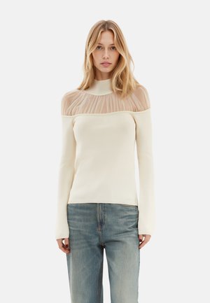 Cremefarbener Langarm-Top mit einem durchsichtigen, gerafften Mesh-Overlay am Ausschnitt. Weicher Strickstoff mit einem einfachen, figurbetonten Design.