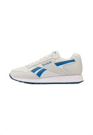 Zapatilla Reebok de color blanco hueso con franjas de logotipo azules, parte superior de malla y cuero, entresuela blanca y suela de goma azul, vista desde el lado izquierdo.
