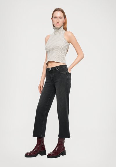 Striped, sleeveless turtleneck top in light gray and white; high-waisted black denim jeans; shiny burgundy ankle boots with chunky heels.