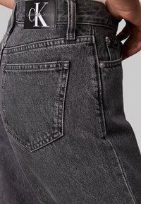 Šedé džíny z denimu s vysokým pasem, výrazným prošíváním a koženou nášivkou značky Calvin Klein Jeans na zadní straně. Design s pěti kapsami.