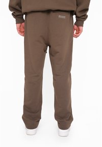 Brune sweatpants lavet af blødt bomuldsblandingsstof, med en afslappet pasform, elastiske manchetter og et lille logo patch på den bageste taljebånd.