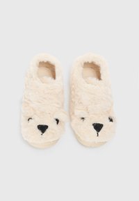 Pantofole pelose color crema con design di faccia d'orso, caratterizzate da occhi neri ricamati, un naso e piccole orecchie sul davanti.