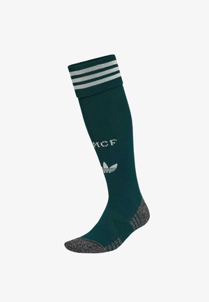 Chaussette haute vert foncé avec un bout et un talon gris, trois bandes blanches en haut, logo Adidas blanc et texte partiel sur la jambe.