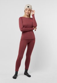 Bordeaux thermoset met lange mouwen top en leggings, gemaakt van rekbare stof. Bevat een aansluitend ontwerp en een klein logodetail.