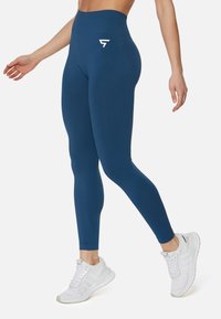 Leggings a vita alta di colore navy realizzati in tessuto elasticizzato con texture a coste, caratterizzati da un logo bianco sull'anca e un design elegante e aderente.