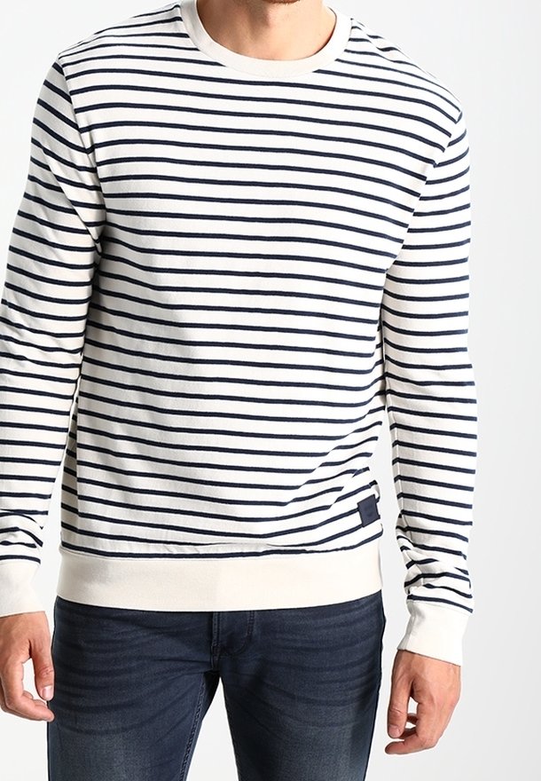 Pull à manches longues rayé bleu marine et blanc en tissu doux. Comprend des poignets et un ourlet côtelés, avec une petite étiquette à la taille.