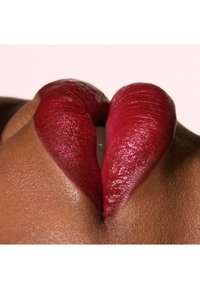 Des lèvres rouge vif avec une finition brillante, présentant une texture lisse et une forme définie, sur un fond neutre.