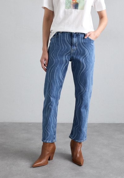 Blauwe spijkerbroeken van denim met golvende witte stiksels, een recht model en een raw hem, gecombineerd met bruine enkellaarsjes.
