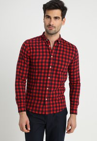 Camisa de cuadros rojo y negro con mangas largas, cuello de botones y cierre frontal con botones; fabricada en algodón con una textura suave y un ajuste entallado.