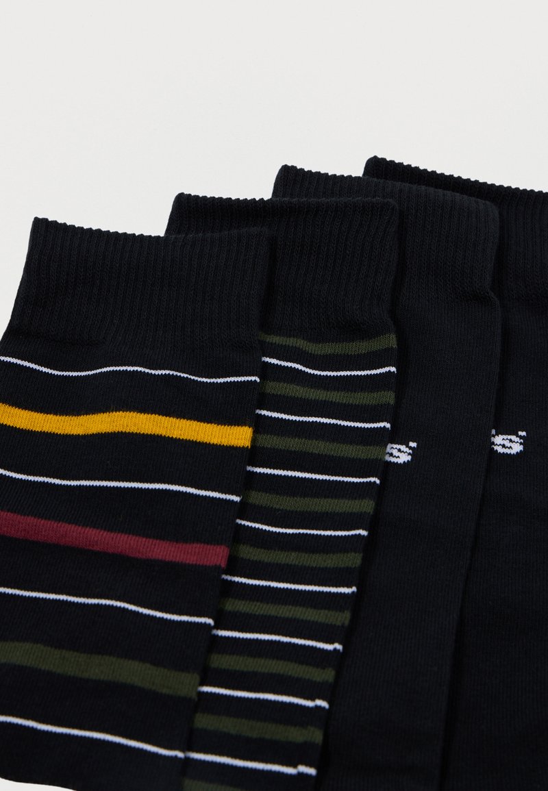 Vier paar sokken in donkere kleuren, met verschillende patronen: één met horizontale strepen in geel, kastanjebruin en wit, een ander met smalle groene en witte strepen.