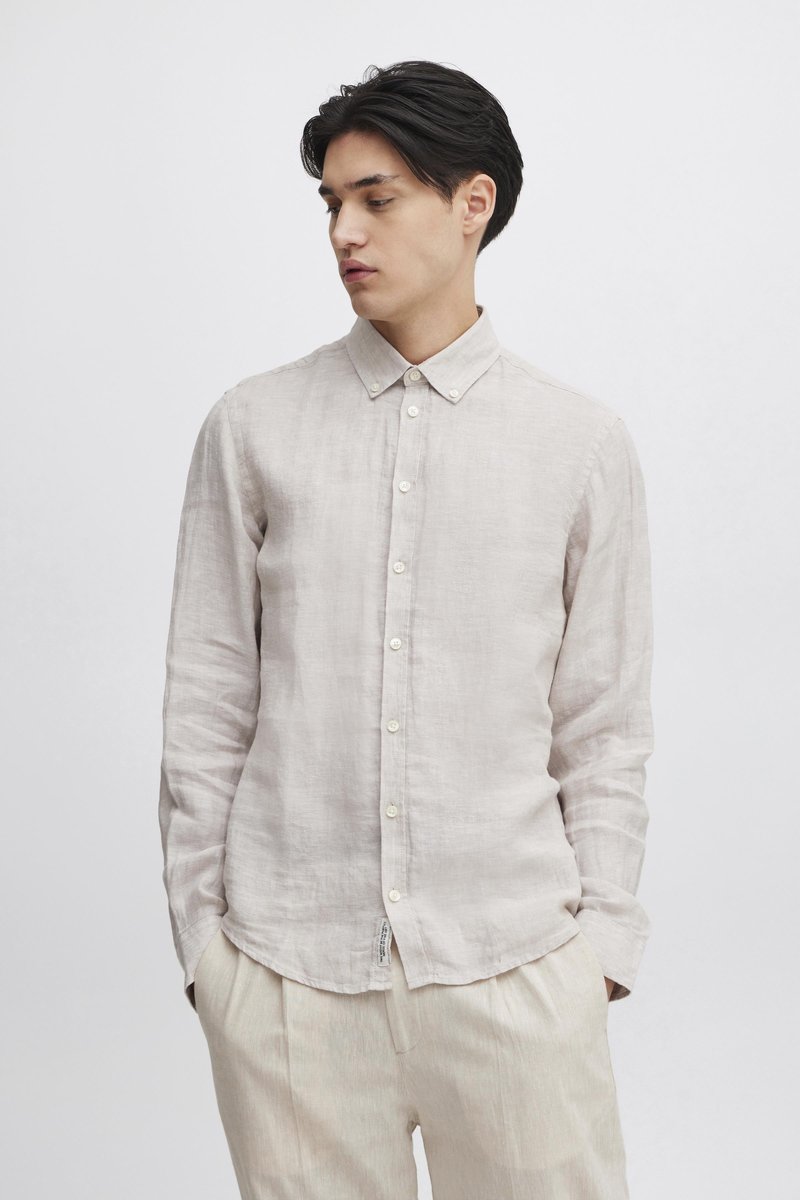 Lysebeige linnedragt med knaplukning ved kraven, lange ærmer og knapper foran. Blød tekstur, minimalistisk design og afslappet pasform.