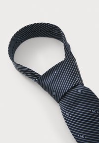 Cravate bleu marine avec des rayures blanches diagonales et de petits accents de logo, fabriquée en tissu lisse avec une forme classique étroite et un design noué.