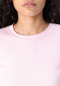 Light pink cotton t-shirt with a round neckline and ribbed texture. The fabric appears soft and smooth. No notable patterns or accents.