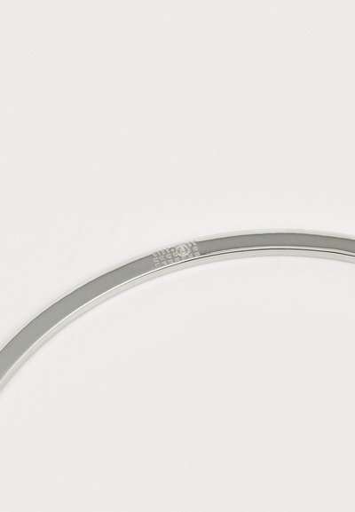 Bracelet en argent with une surface lisse et polie, présentant une gravure subtile le long du bord. Design simple et circulaire sans accents supplémentaires.