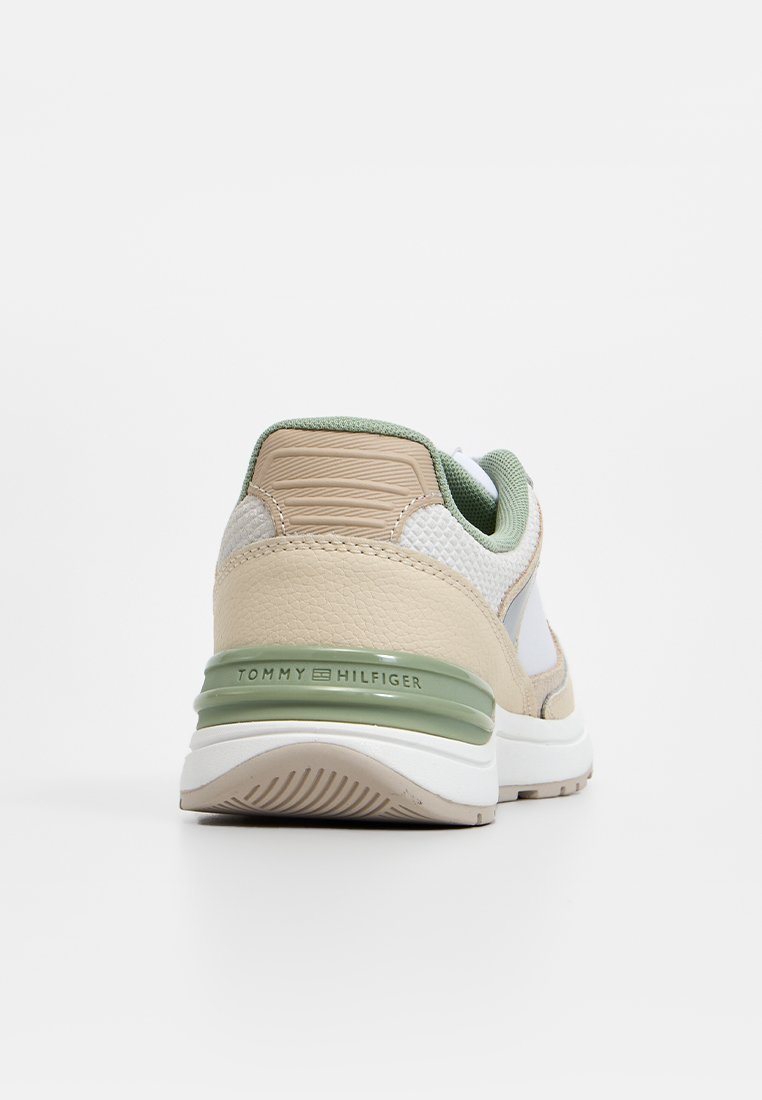 Sneaker mit einem Obermaterial aus beigem Leder und Mesh, Akzenten in Grün und einer weißen Sohle, mit einem sichtbaren Markenlogo auf der Ferse.