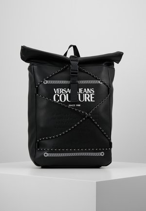 Czarny plecak z górną klapą na zwijanie, z przodu ze szczegółami z linki bungee i białym logo tekstowym Versace Jeans Couture.