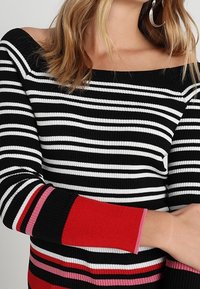 Mustat ja valkoiset raidalliset ribbipaidat, joissa on olkapäitä paljastava muotoilu. Ominaisuuksiin kuuluu värikkäät punaiset, vaaleanpunaiset ja violetit yksityiskohtaraitat hihoissa.