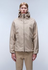 Beige vattentät jacka med hög krage, dragkedja fram och justerbar huva. Har också dragkedjefickor och en elegant, slät textur.