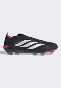 Μαύρο ποδοσφαιρικό παπούτσι Adidas Predator με λευκές ρίγες, κόκκινες λεπτομέρειες και διάφανα καρφιά, απεικονίζεται σε πλάγια όψη σε λευκό φόντο.
